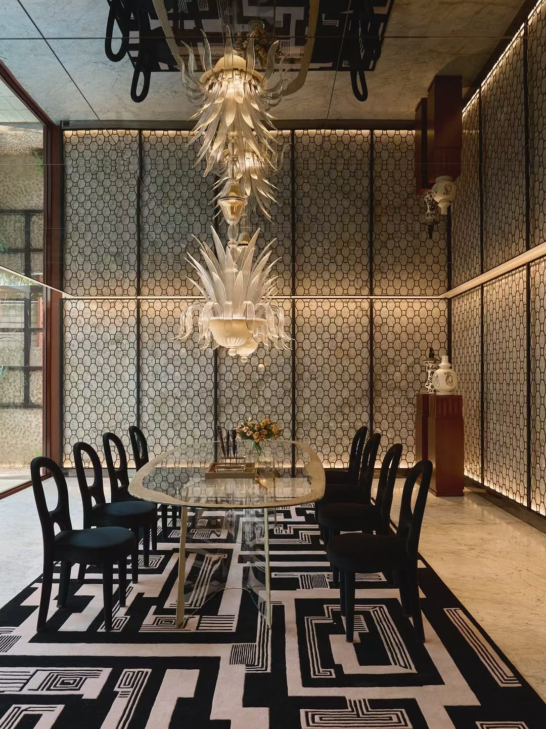 Private residence dining room with a centered table, graphic rug and sculptural suspended lighting